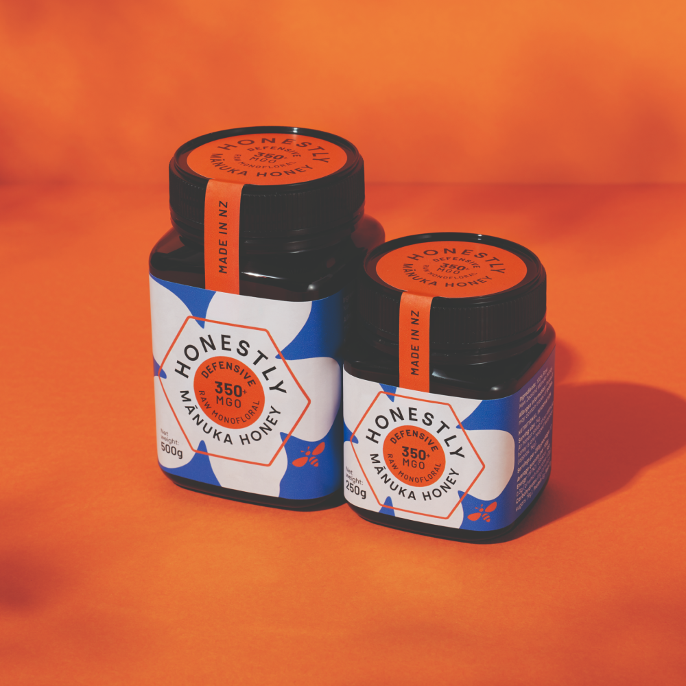 Two jars of 'Honestly' 350+ MGO Manuka Honey on an orange background