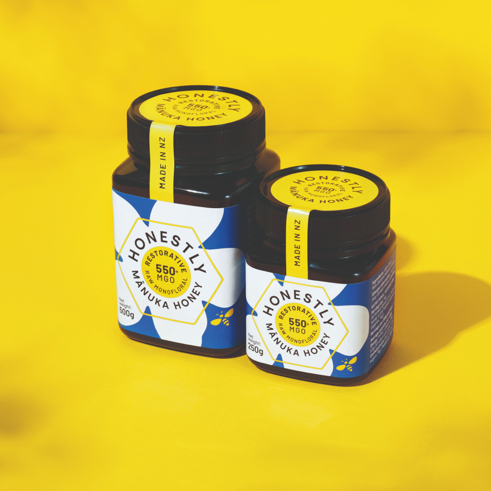 Two jars of Honestly 550+ MGO Manuka Honey on a yellow background